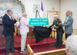 Senator Pat Stefano and Rep. Jesse Topper join veterans as the PFC Charles O. Snyder Memorial Bridge sign is unveiled during a bridge dedication ceremony in Bedford County.